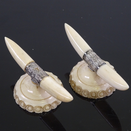 212 - A pair of ivory and silver knife rests, in the form of horns and carved base, width 7cm.