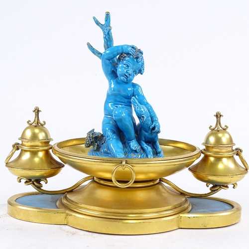 282 - An ornate 19th century French gilt-metal desk stand, surmounted by a blue glazed ceramic cherub and ... 