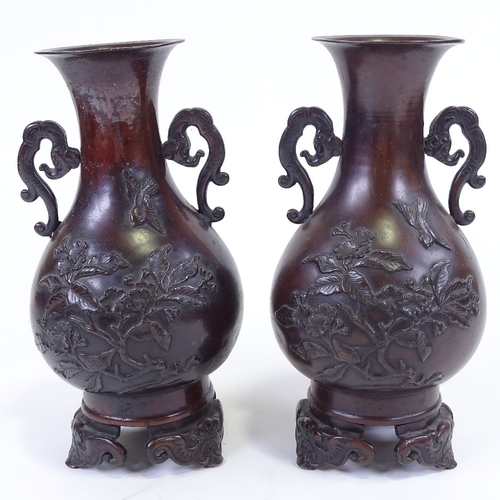 284 - A pair of Japanese 19th century patinated bronze vases, with relief moulded prunus decoration, on ca... 