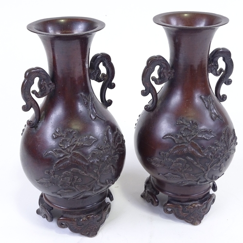 284 - A pair of Japanese 19th century patinated bronze vases, with relief moulded prunus decoration, on ca... 