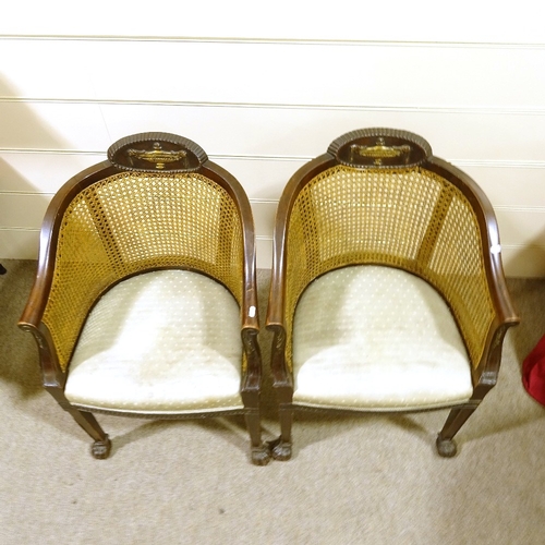 293 - A pair of early 20th century mahogany-framed bergere tub chairs, with cane-panelled backs and carved... 