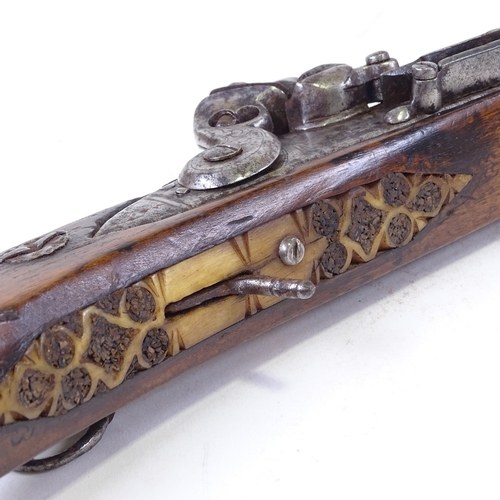 298 - An 18th century Middle Eastern flintlock rifle, with carved walnut stock and carved horn trigger pla... 