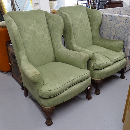 1829 - A pair of Edwardian upholstered wingback fireside armchairs, on carved cabriole legs, with hoof feet