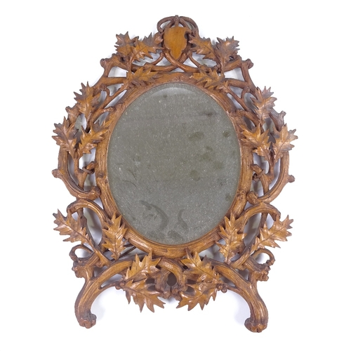 211 - A 19th century Black Forest carved wood-framed oval wall mirror, in holly decorated surround, height... 