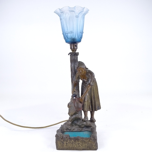 339 - A patinated spelter table lamp in the form of a woman at a fountain, with blue glass shade, overall ... 