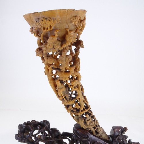 300 - A 19th century Chinese rhinoceros horn full tip cup, carved and pierced all over with Oriental figur... 