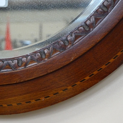 766 - An oval inlaid mahogany framed bevelled wall mirror, 86cm