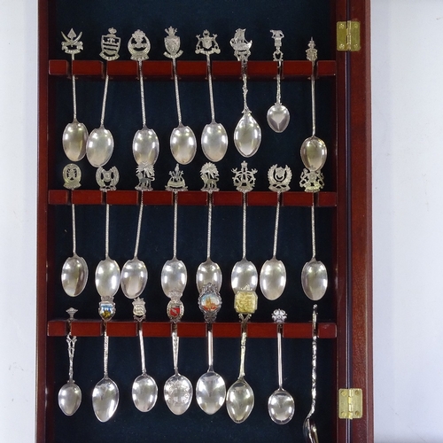 194 - A glazed mahogany cabinet containing silver and plated souvenir spoons