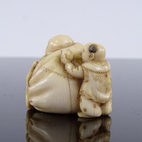 293 - A Japanese ivory netsuke in the form of a man and child resting on a sack, Meiji Period, length 4cm