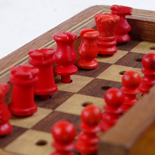 430 - A small mahogany travelling chess set, with red and white stained bone pieces, length 13cm