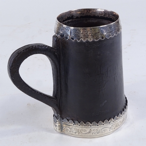 443 - A rare early leather tankard, with engraved unmarked silver mounts and armorial crest, height 16.5cm