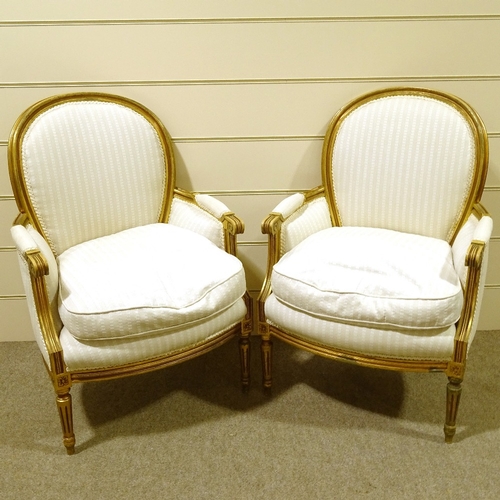 113 - A pair of French carved giltwood-framed salon armchairs, recently re-upholstered in pale striped fab... 