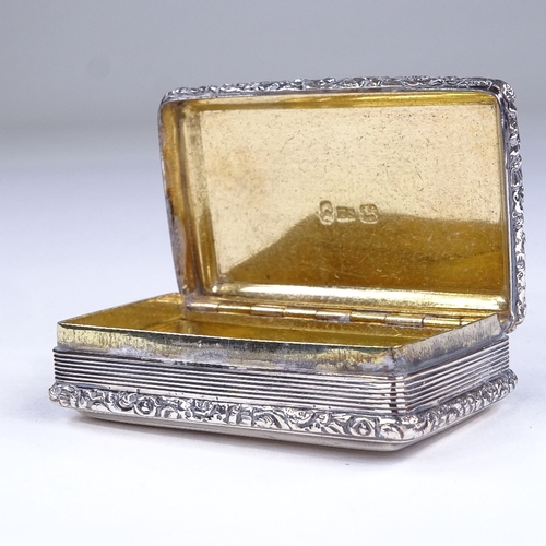 600 - A George IV rectangular silver snuffbox, allover reeded decoration with cast floral border and gilt ... 