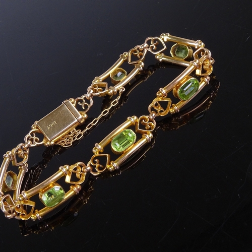 646 - An Art Nouveau 15ct gold peridot bracelet, emerald-cut peridots flanked by tube boarder and scrolled... 