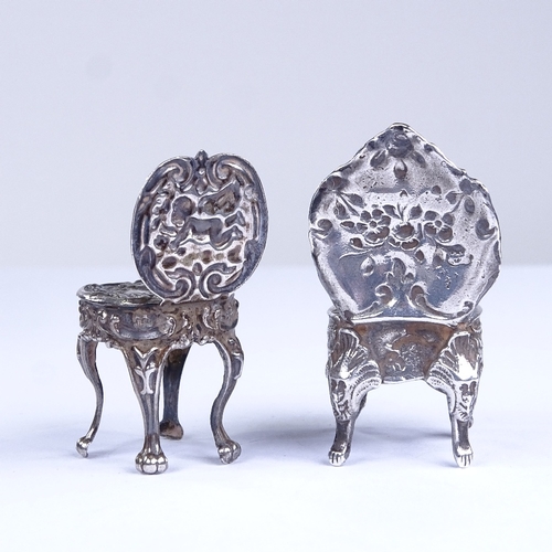 663 - 2 miniature silver doll's house chairs, allover relief embossed foliate decoration, with lion paw fe... 