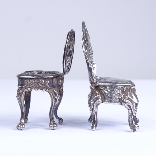 663 - 2 miniature silver doll's house chairs, allover relief embossed foliate decoration, with lion paw fe... 