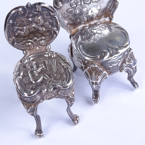 663 - 2 miniature silver doll's house chairs, allover relief embossed foliate decoration, with lion paw fe... 