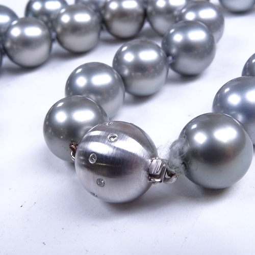 687 - A single-row Princess length black pearl necklace, with 18ct white gold diamond set sphere clasp, pe... 