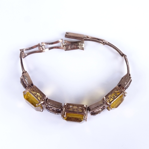 748 - A mid-20th century unmarked gold yellow stone and white sapphire panel bracelet, with pierced scroll... 