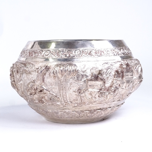 761 - An early 20th century large Burmese silver rice bowl, high relief body depicting hunting lion scenes... 