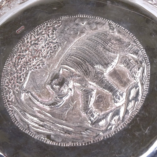 761 - An early 20th century large Burmese silver rice bowl, high relief body depicting hunting lion scenes... 