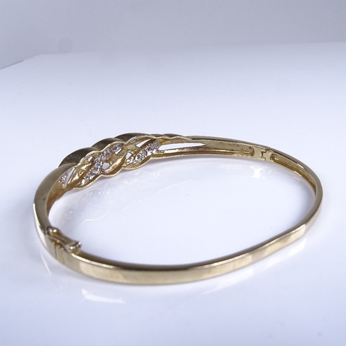 786 - A late 20th century unmarked gold diamond crossover hinged bangle, total diamond content approx 0.25... 