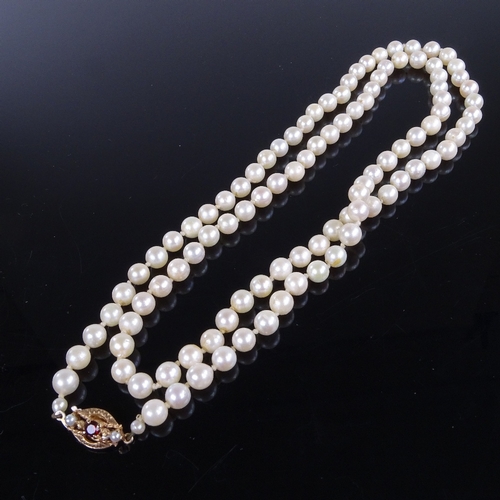 788 - A late 20th century single-strand opera length cultured pearl necklace, on 9ct gold garnet clasp, ne... 