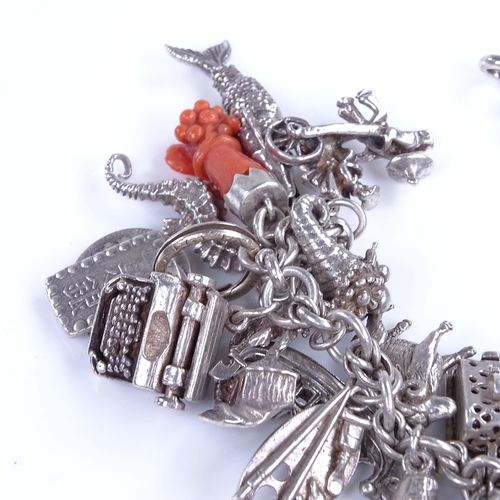 913 - An unmarked silver fancy link charm bracelet, with 31 assorted silver charms, bracelet length 19cm, ... 