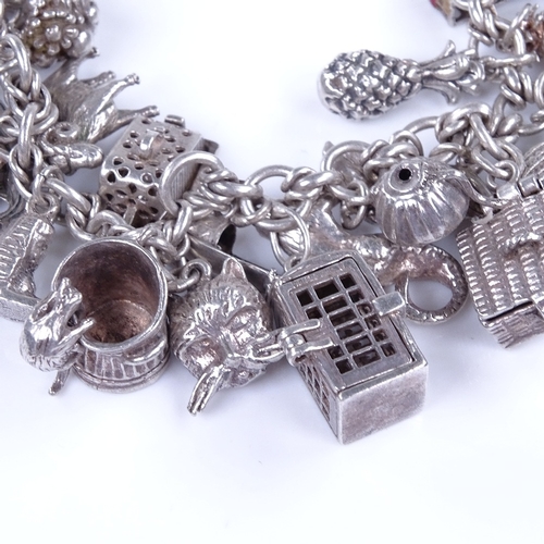 913 - An unmarked silver fancy link charm bracelet, with 31 assorted silver charms, bracelet length 19cm, ... 