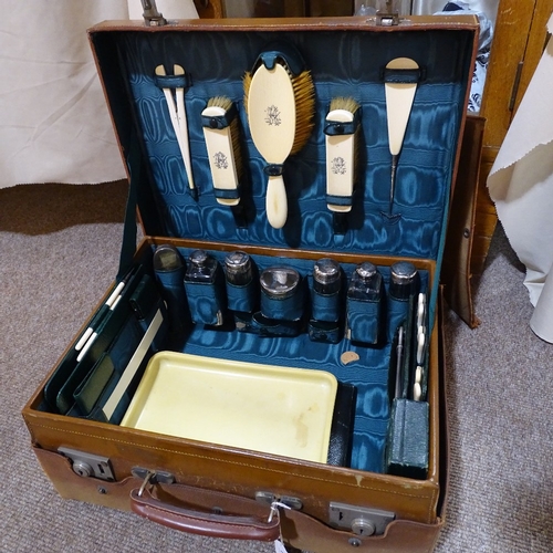 66 - A gentleman's leather travelling case, the interior fitted with original silver-topped cut-glass toi... 