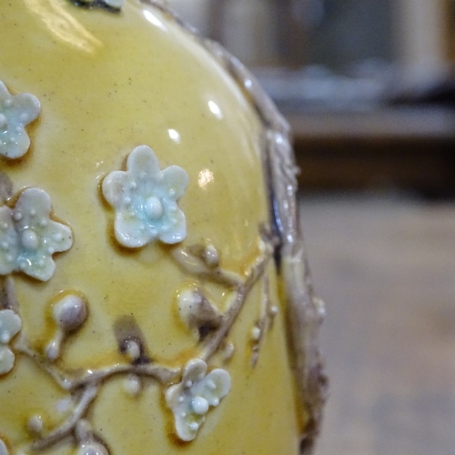 323 - A Chinese yellow glaze narrow-neck vase, with relief  prunus design, height 18cm