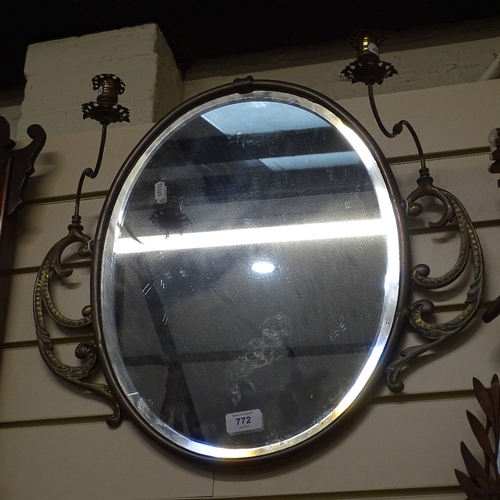 772 - A 19th century brass-framed oval bevel-edge wall mirror, with swivel candlestick fittings, overall h... 