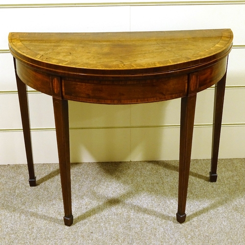 281 - A George III mahogany demilune fold over card table, with tapered legs and spade feet