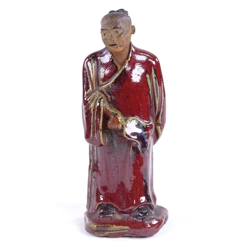 115 - An 18th century pottery figure of a man with sang de boeuf glaze robes, height 18cm