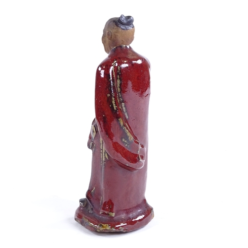 115 - An 18th century pottery figure of a man with sang de boeuf glaze robes, height 18cm