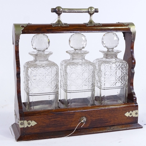 334 - A Victorian oak 3-bottle tantalus, with electroplate mounts and square cut-glass decanters, length 3... 