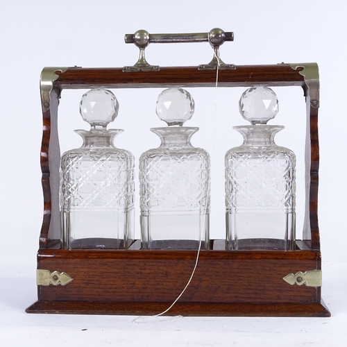 334 - A Victorian oak 3-bottle tantalus, with electroplate mounts and square cut-glass decanters, length 3... 