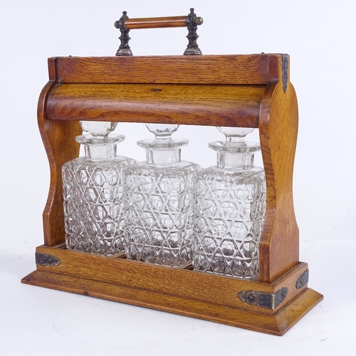 335 - A Victorian oak 3-bottle tantalus, with electroplate mounts and glass decanters, length 32cm (A/F)