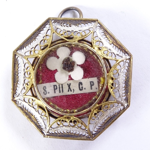 488 - A religious reliquary pendant in unmarked metal filigree surround, 32mm across, leather case