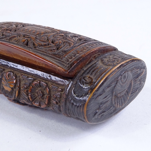 493 - A 19th century coquilla nut snuffbox, all over relief carved musical instruments in floral border, l... 