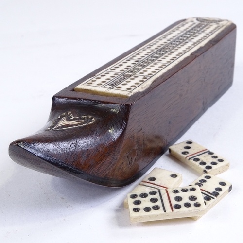 496 - A 19th century carved wood shoe design games box, with bone cribbage board sliding lid enclosing a s... 