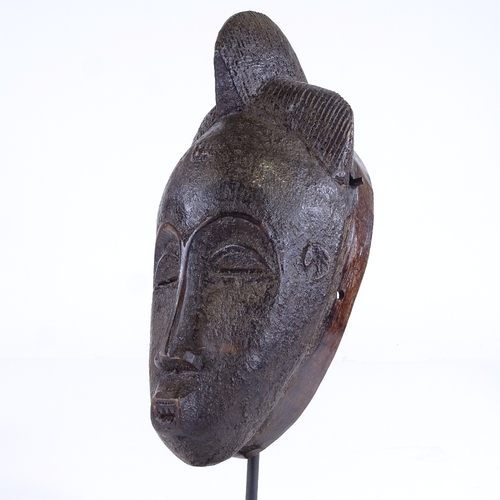 522 - A small African carved wood mask, height 25cm, on modern stand