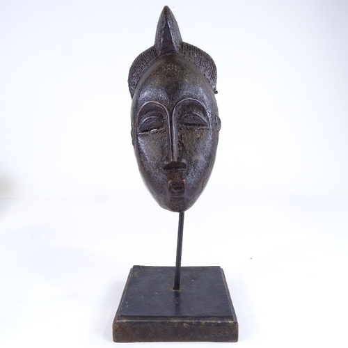 522 - A small African carved wood mask, height 25cm, on modern stand