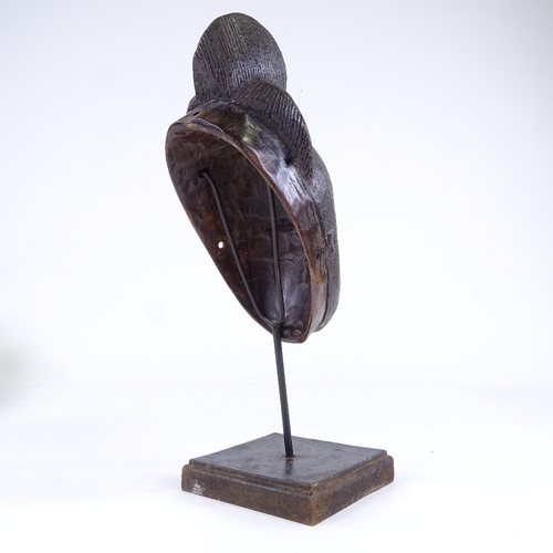 522 - A small African carved wood mask, height 25cm, on modern stand