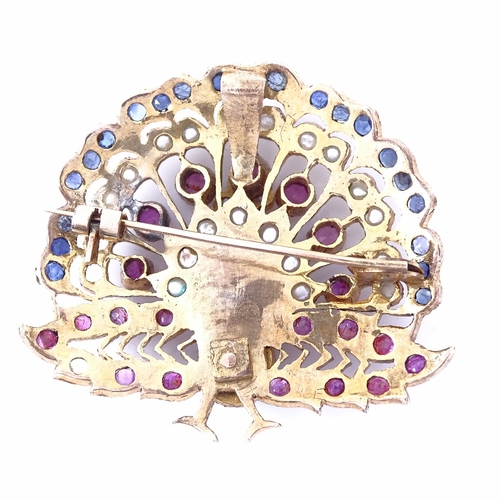 1158 - An Indian unmarked yellow metal ruby sapphire and pearl peacock pendant/brooch, pendant height 45.3m... 