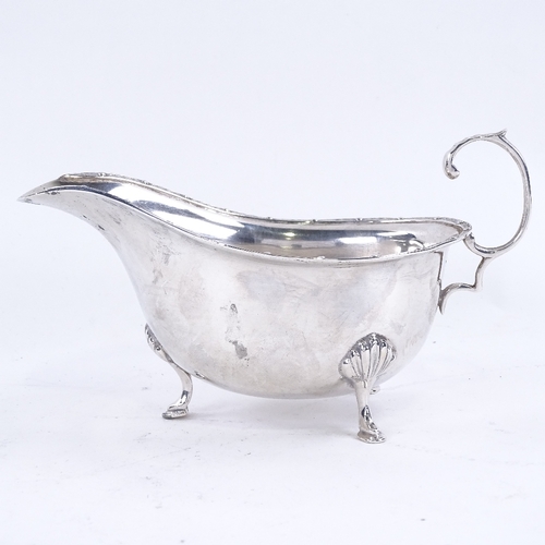 1627 - A George VI silver sauce boat, with engraved rim on 3 shell feet with scrolled acanthus leaf C-handl... 