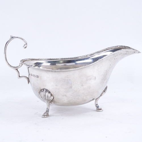 1627 - A George VI silver sauce boat, with engraved rim on 3 shell feet with scrolled acanthus leaf C-handl... 