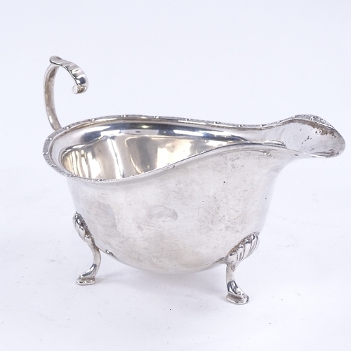 1627 - A George VI silver sauce boat, with engraved rim on 3 shell feet with scrolled acanthus leaf C-handl... 