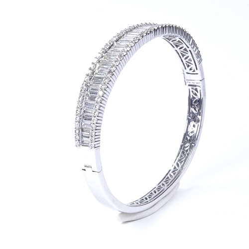 1111 - A 7.5ct diamond cluster hinged bangle/bracelet, set with graduated baguette diamonds within a round ... 