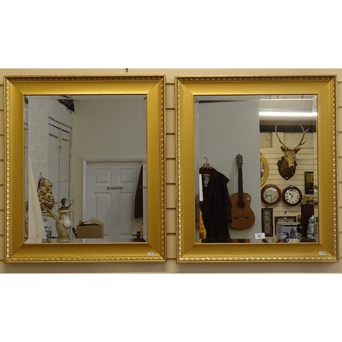 64 - A modern pair of rectangular gilt-framed bevel-edge wall mirrors, 74cm x 64cm